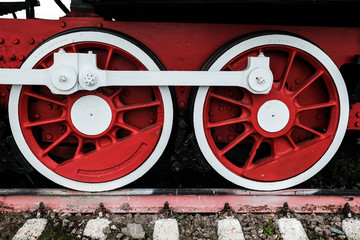 Red wheels of an old Russian locomotive on the rails close-up.