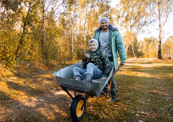 Dad spends time with his son, a happy little boy pushed by a dad. Active outdoor games for children in the fall.