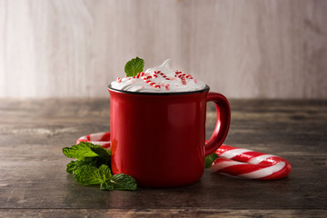 Peppermint coffee mocha decorated with candy canes for Christmas on wooden table.