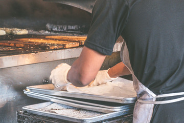 USA, New york: Traditional bagel bakery. Baker in the process of preparing authentic New York style bagels with sesame for baking in the oven.