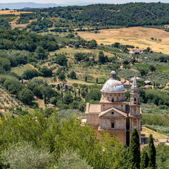 Fototapeta na wymiar A church In Montalcino Tuscany With Trees, Vineyards, Crops And Hills in the Background