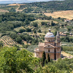 Fototapeta na wymiar A church In Montalcino Tuscany With Trees, Vineyards, Crops And Hills in the Background