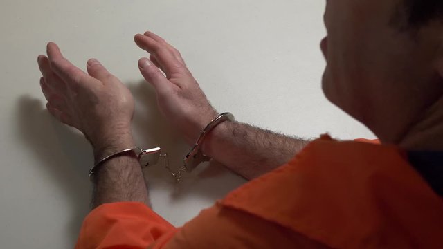 Confessing criminal dressed in prison orange uniform. Talking and explaining something.