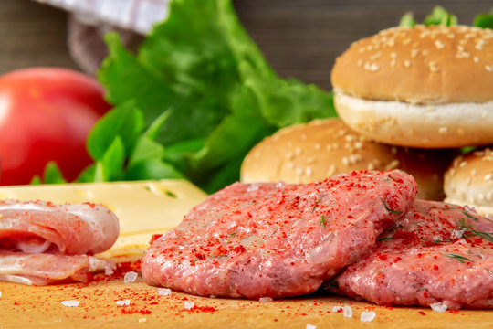 Process of cooking homemade burgers, meatballs, tomatoes, cheese and other ingredients on a wooden background, close up