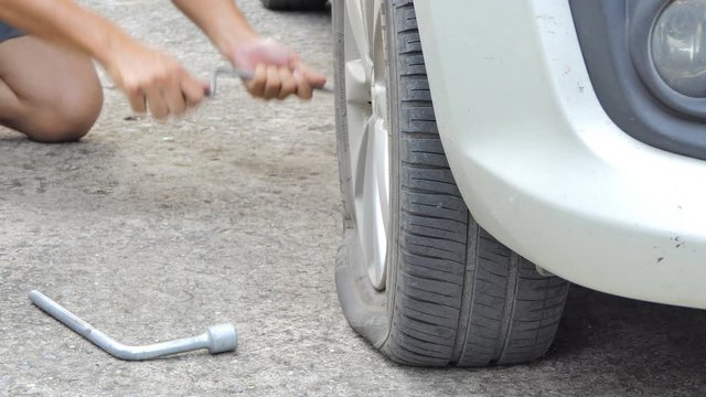 Driver changing a wheel, flat tire, in roadside. real life on street.