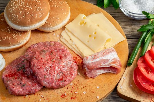 Process of cooking homemade burgers, meatballs, tomatoes, cheese and other ingredients on a wooden background, close up