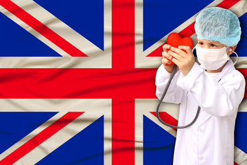 photo of a child with a stethoscope in a professional uniform with a heart in his hands against...