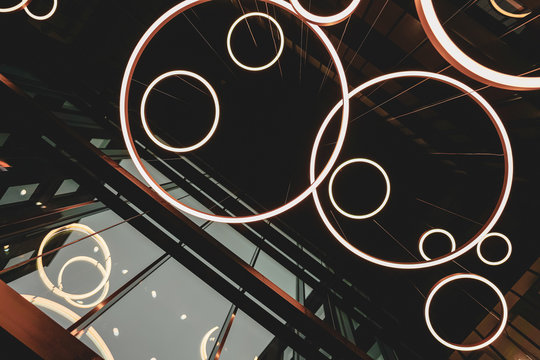 Light ring fixtures hanging from the building ceiling, dark architectural concept photo
