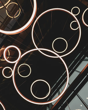 Light ring fixtures hanging from the building ceiling, dark architectural concept photo