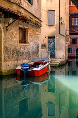 Fototapeta na wymiar Narrow canals in Venice with docked boats, Italy