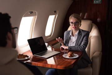 professional business colleagues working with laptop in airplane