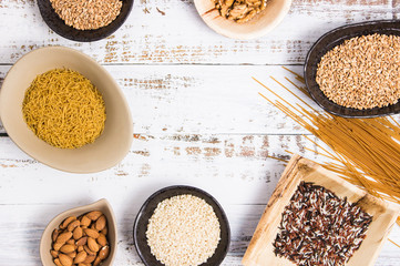 Different kind of whole grains in bowls  and whole spaguetti arranged in a white table