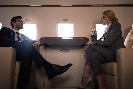 executive professional business colleagues in suits sitting in plane - Powered by Adobe
