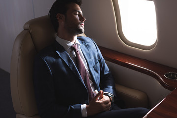 businessman sleeping in airplane during business trip