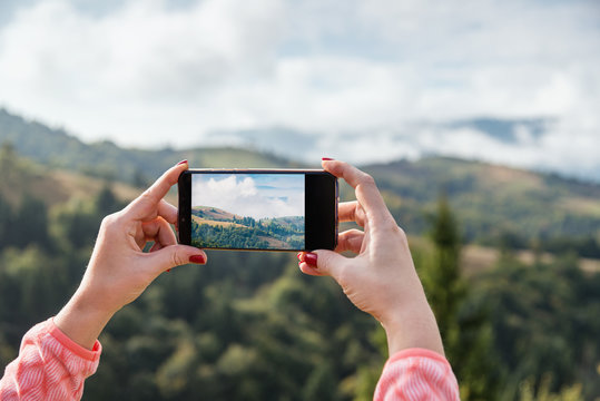 Woman taking picture in mountains using smart photne