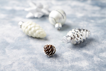 Pine cone and silver Christmas baubles. Christmas decoration on bright wooden background. Close up. 