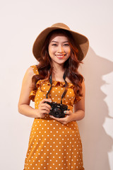 Image of young photographer woman isolated over beige background wall holding camera.