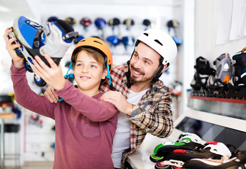 father and son deciding on new roller-skates in sports store