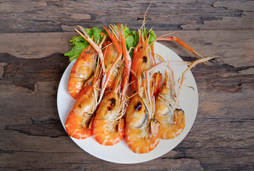 Grilled shrimp and seafood sauce is very tasty on a white plate on a wooden background.