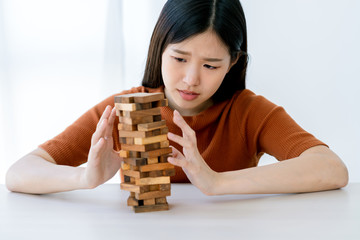 worry stress asian smart woman try to built and protect wooden stack tower risk management strategy...