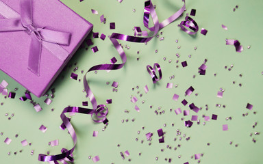 Present box on mint background with shiny confetti. Holiday and festive backdrop. Flat lay style