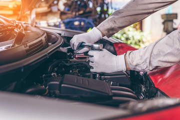 Naklejka premium mechanic Engine check concept. Close up hand doing car service. Tight nut by socket block.