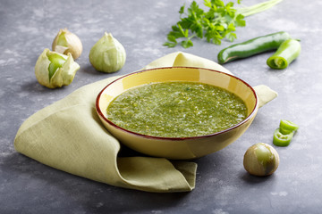 Tomatillo salsa verde. Bowl of spicy green sauce on gray table, mexican cuisine. - obrazy, fototapety, plakaty