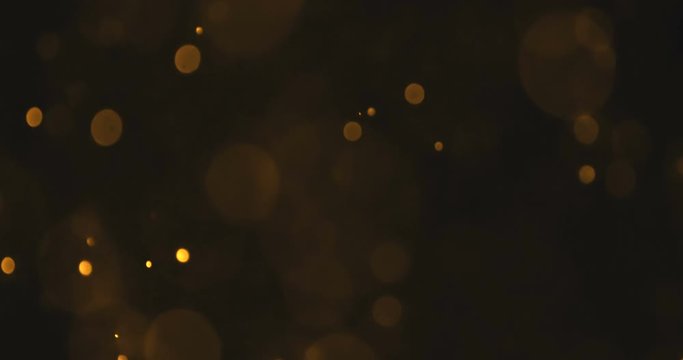 abstract gold glow particles bokeh flowing effect on black background, holiday happy new year event