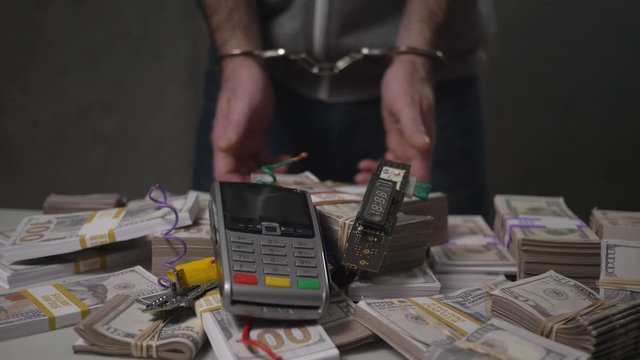 Credit card hacker getting caught by the police with cash money and a hacked credit card terminal.