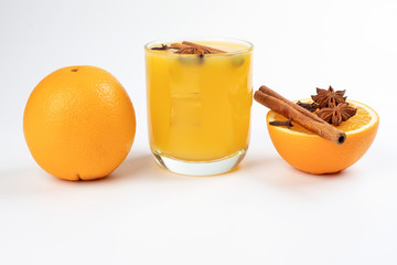 Fresh orange cinnamon star anise clove spice juice in glass on white yellow background