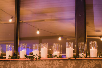 Coziness and style. Modern event design. Table setting at wedding reception. Floral compositions with beautiful flowers and greenery, candles, laying and plates on decorated table.