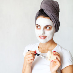 Smiling woman applying clay mask