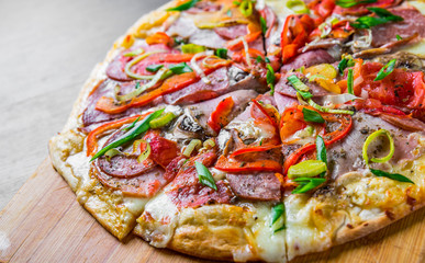 Pizza with Mozzarella cheese, ham, tomato, salami, onion, pepper, Spices. Italian pizza on wooden table background