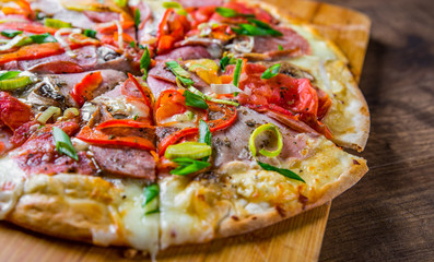 Pizza with Mozzarella cheese, ham, tomato, salami, onion, pepper, Spices. Italian pizza on wooden table background