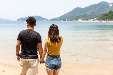 ビーチで手を繋ぐカップル