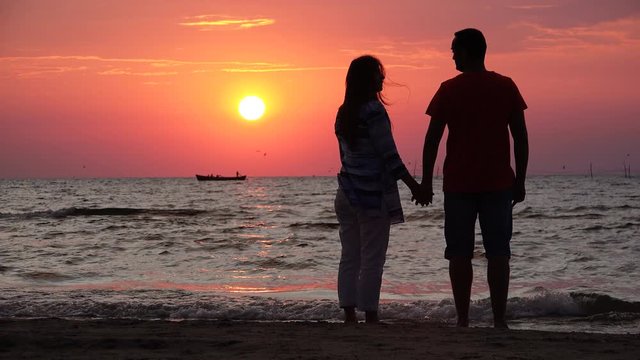 Couple of lovers silhouettes standing at seashore and enjoy sunset, happy foe new beggining