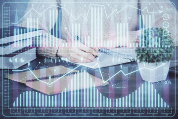 Forex graph on hand taking notes background. Concept of research. Double exposure
