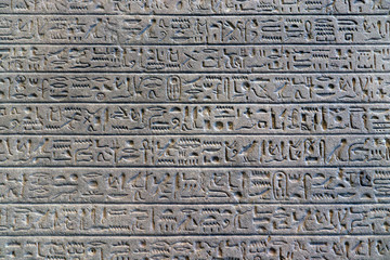Egyptian hieroglyphs on the wall. Ancient letter pattern in cold grey colors