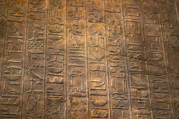 Old egypt hieroglyphs carved on the stone. Ancient letter pattern in warm yellow tones