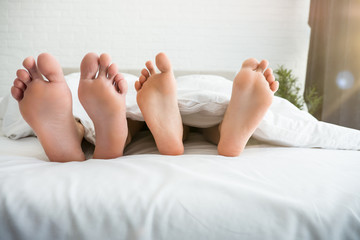 man and woman barefeet lying in the bed