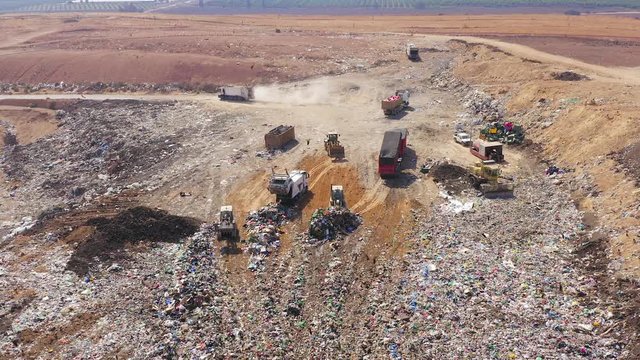 Aerial footage of a Municipal Solid waste Landfill during collecting, sorting and pressing work, with a massive flock of birds.