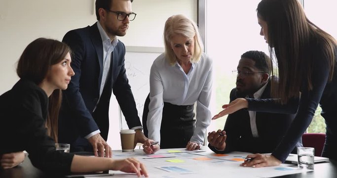 Serious multiracial team with female manager brainstorming on paperwork
