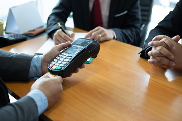 Close up of hands businessman use a credit card swipe to pay for the share transfer fees in the...