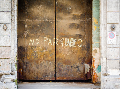 Large steel rusty doors in Havana, Cuba with no parqueo sign