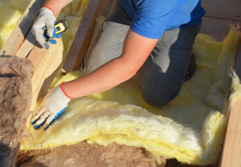 Contractor Insulating with Mineral Wool Attic Roof. Close up on insulation layers of mineral wool...