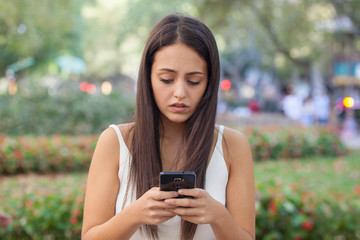Sad girl reading phone message on the street