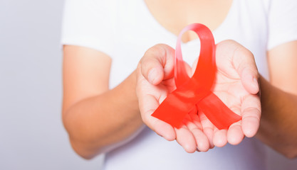 Closeup of female with red ribbon Support HIV AIDS on hands