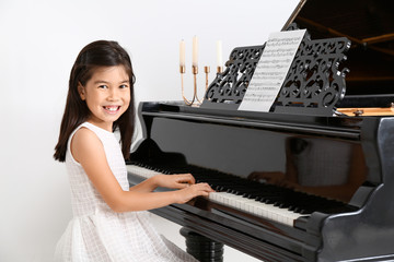 Little girl playing grand piano at home