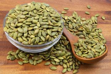 Pumpkin seeds with wooden spoon and glass bowl