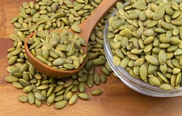 Pumpkin seeds with wooden spoon and glass bowl